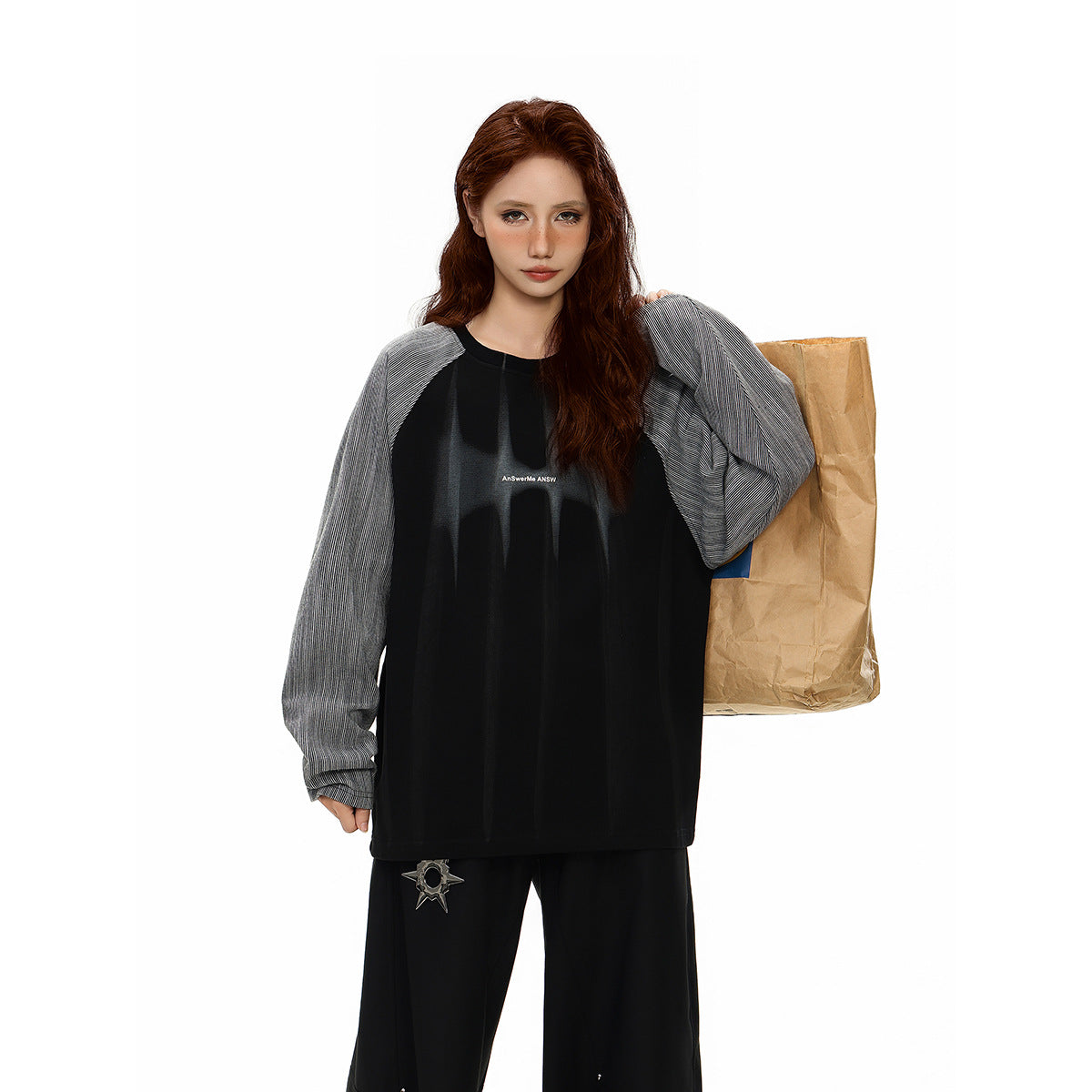 Model wearing an oversized black top with gray pinstriped raglan sleeves and wide black pants.