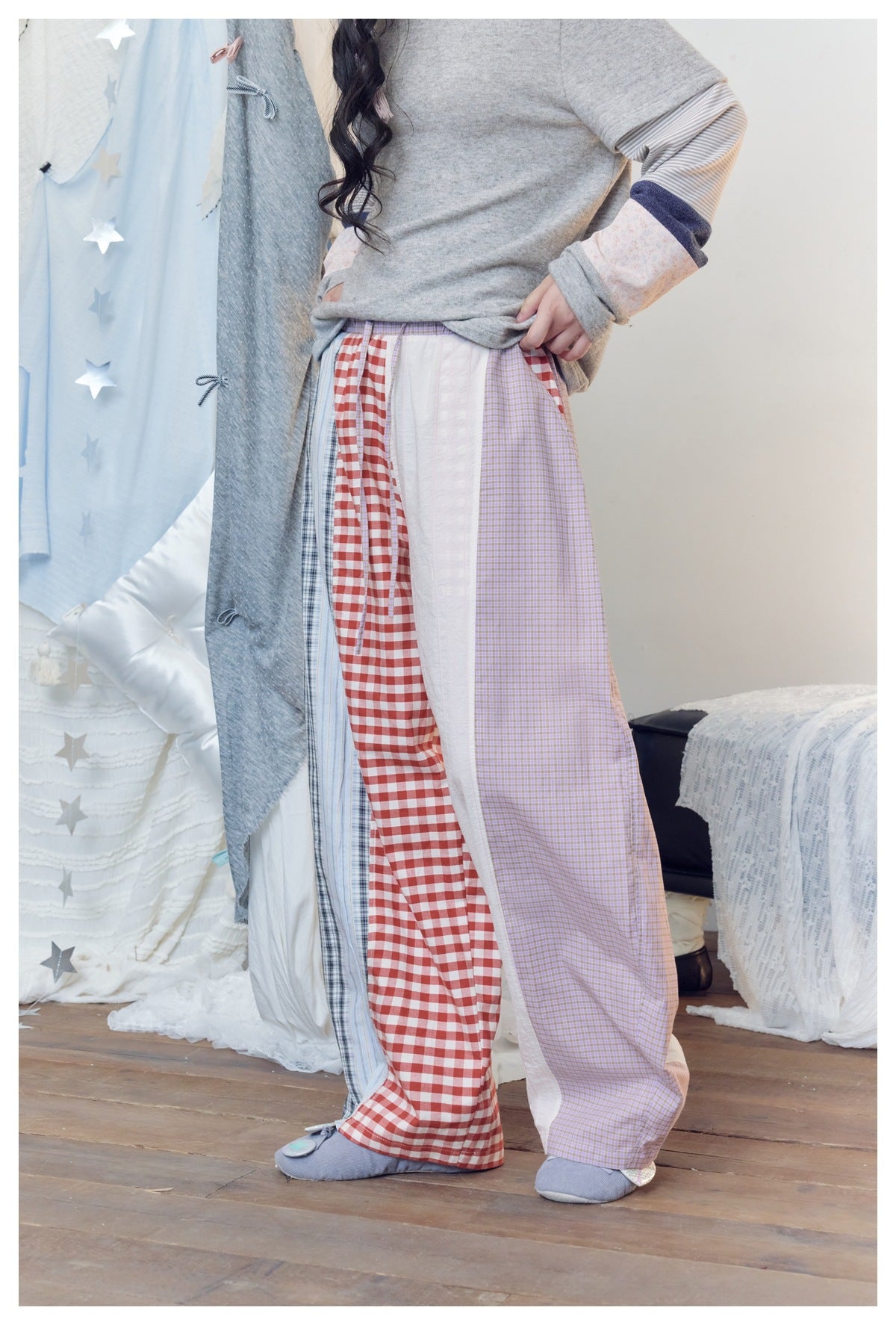 Model wearing wide-leg patchwork pants with red gingham, lavender checks, pale stripes and white panels.