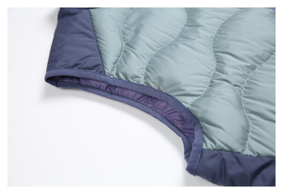 Close-up of the vest's bound armhole edge, navy trim, and quilted green-blue body.