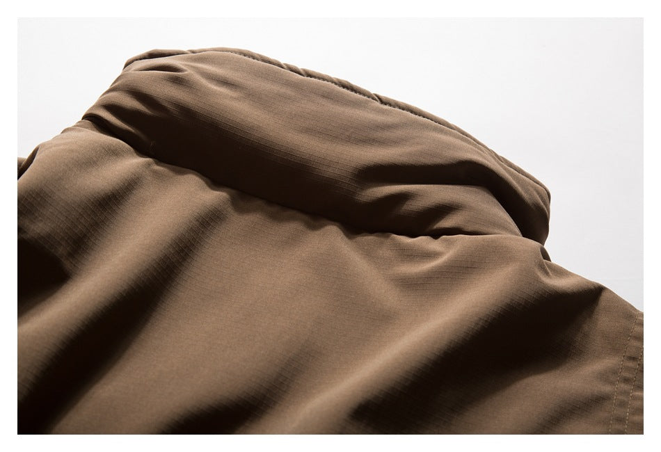 Close-up of brown jacket fabric showing its subtle grid texture and folded, stitched panels.