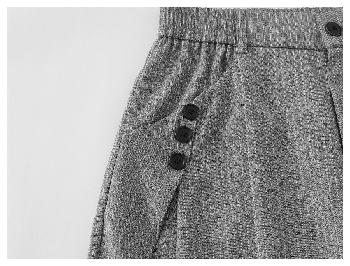 Close-up of gray pinstriped trousers showing the elastic waistband, side pocket opening, and black buttons.