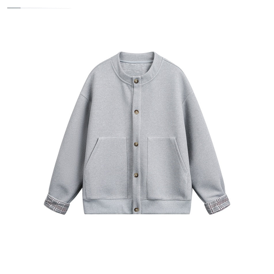 Gray button-front textured jacket with stand collar, front pockets and gray plaid cuffs, flat lay