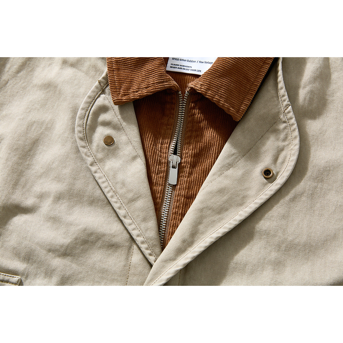 Close-up of the beige jacket's front zipper, brown corduroy lining and snap-fastened storm flap.