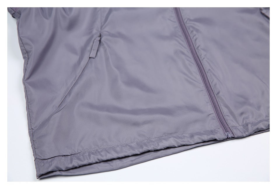 Close-up of the gray-lavender jacket's front zipper, angled pocket opening, and elasticized hem.