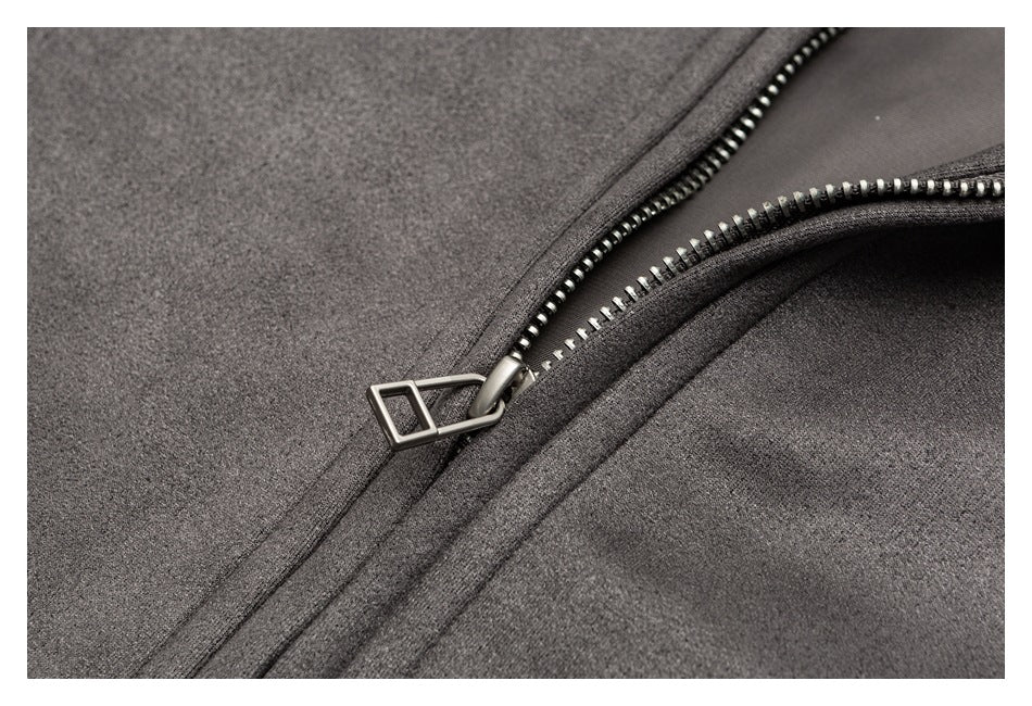 Close-up of a partly open silver-toothed zipper on charcoal gray fabric.
