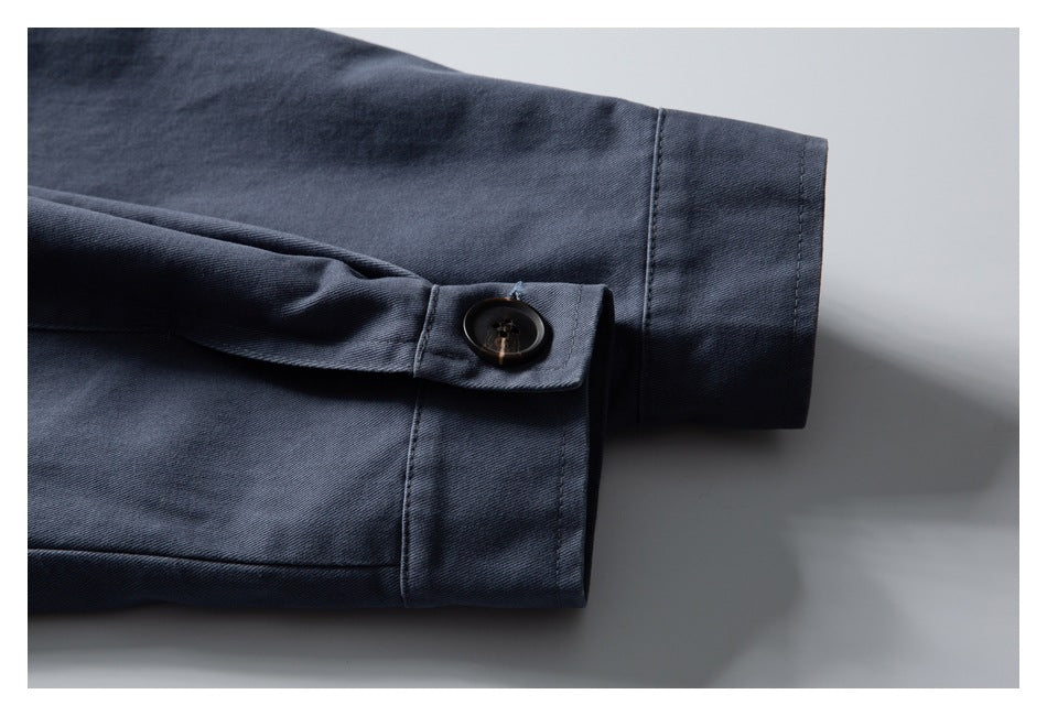 Close-up of a dark blue jacket sleeve with a buttoned cuff tab and neatly stitched hem.