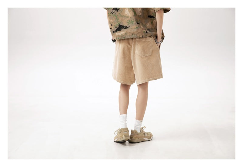 Cropped model wearing light tan knee-length shorts, shown from the back with a single rear pocket.