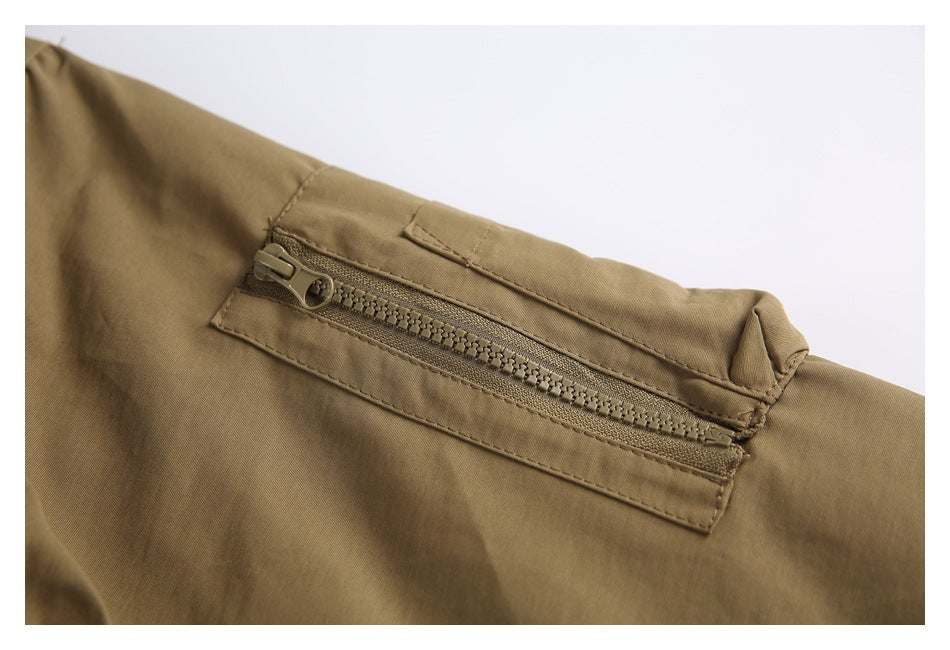Close-up of a khaki jacket's zippered pocket with a chunky zipper and stitched trim.