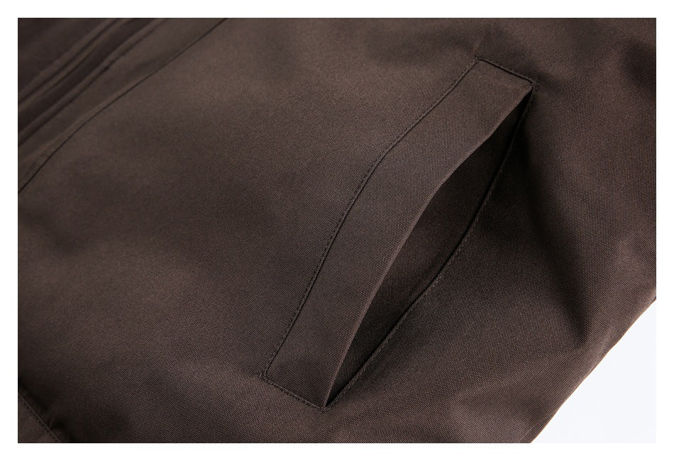 Close-up of a slanted hand pocket on dark brown coat fabric.