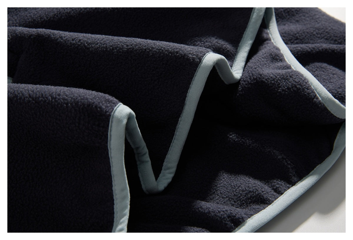 Close-up of dark navy fleece garment edges and seams finished with pale gray binding.