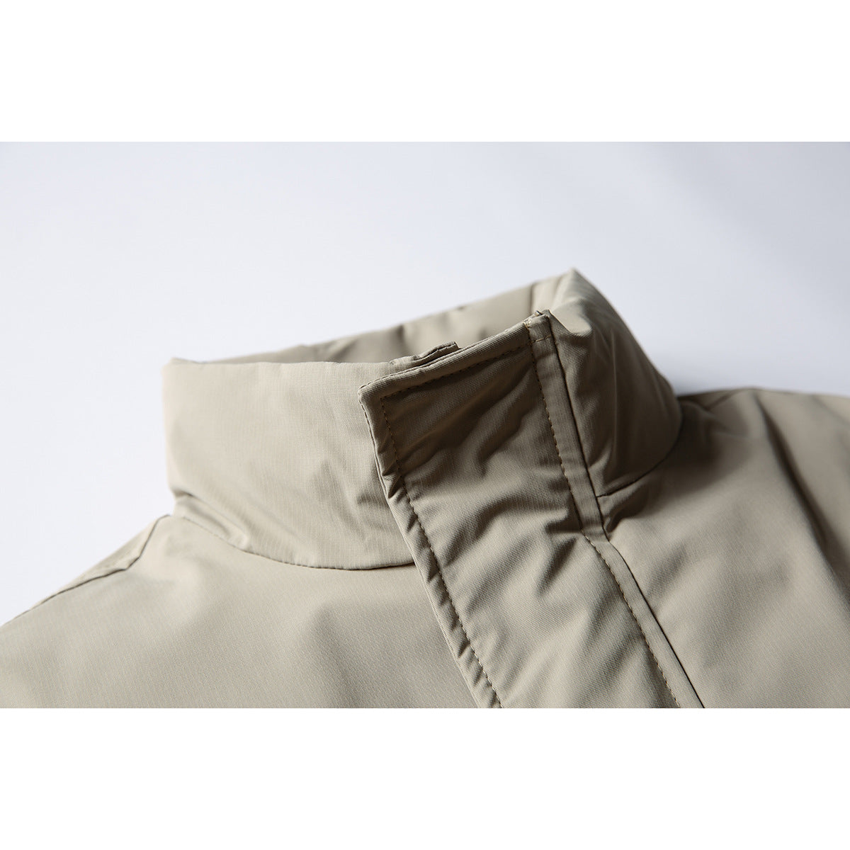 Close-up of a taupe jacket's stand collar and covered front fastening.
