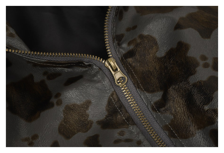 Close-up of a brass-colored zipper on glossy gray-brown spotted garment fabric.