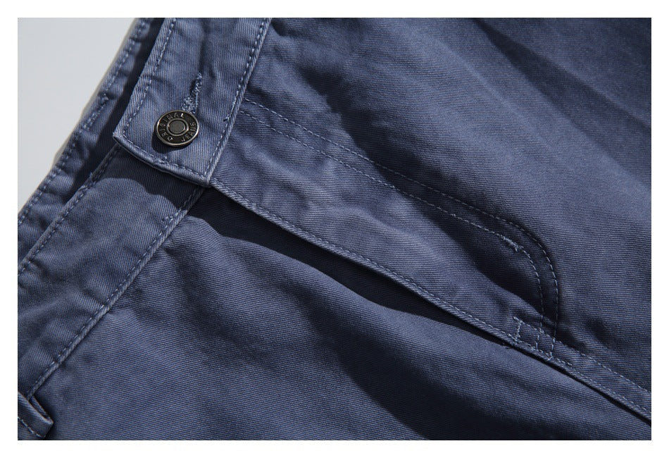Close-up of a dark button and curved pocket opening on navy garment fabric.