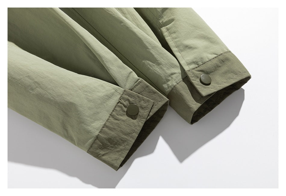 Close-up of two olive-green jacket cuffs with darker trim and snap closures.