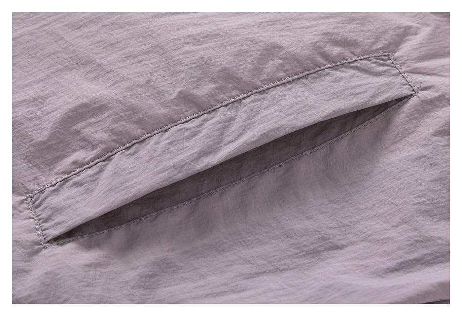 Close-up of a stitched flap pocket on mauve fabric.