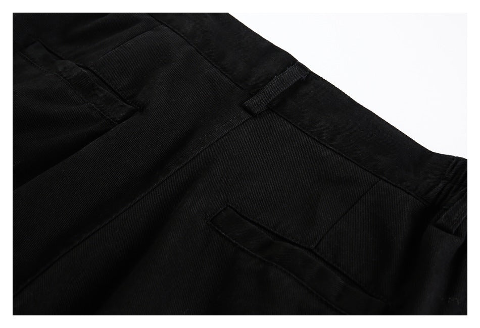 Close-up of black trousers showing the waistband, belt loop, and pocket stitching.