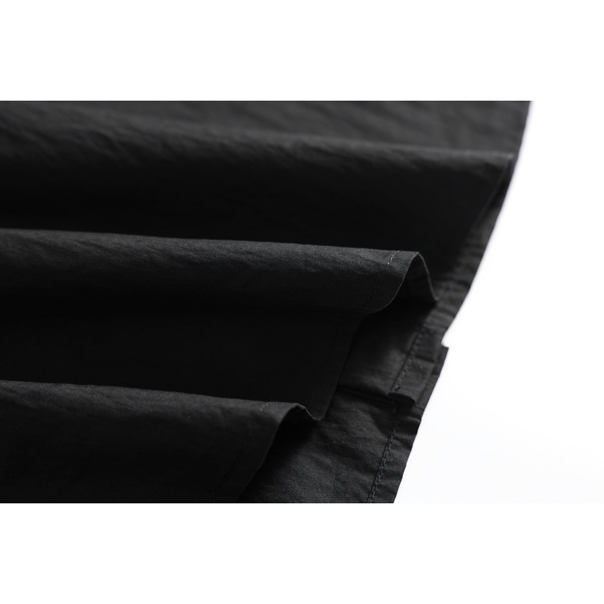 Close-up of black shirt fabric and folded hem stitching.