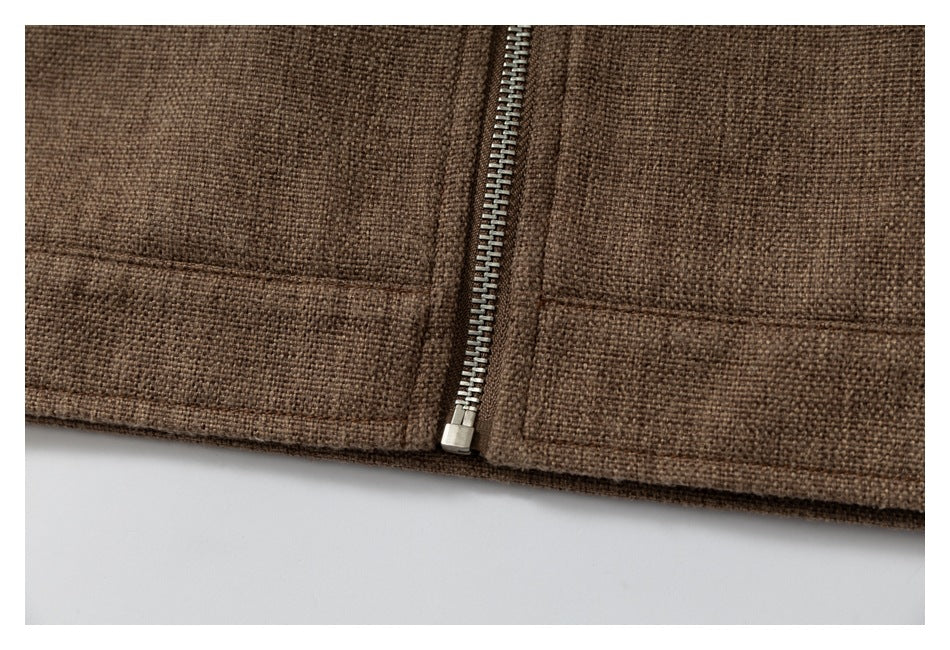 Close-up of a silver zipper and horizontal seam on brown textured fabric.