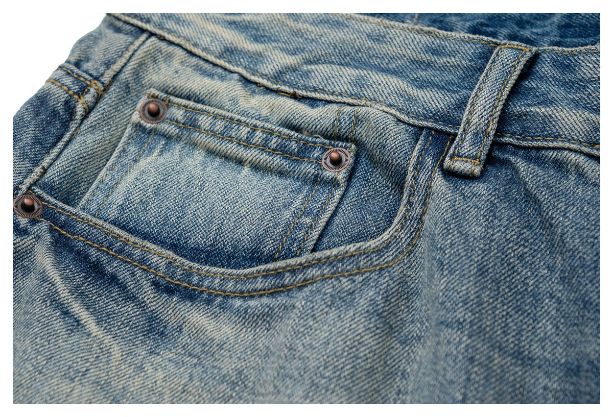 Close-up of faded blue jeans showing a small front pocket with metal rivets and a belt loop.