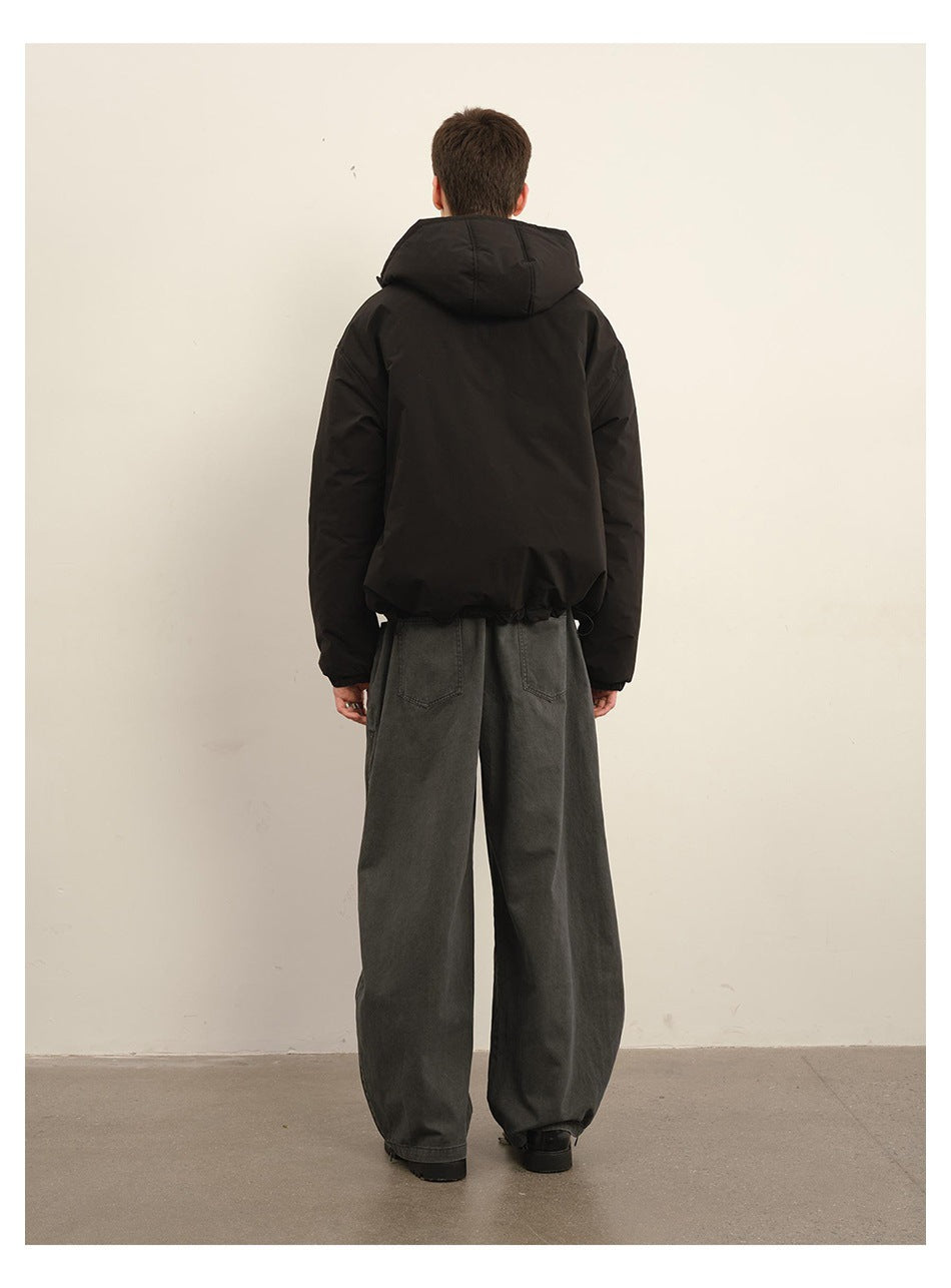 Back view of a model wearing the black hooded jacket with a drawcord hem and wide gray pants