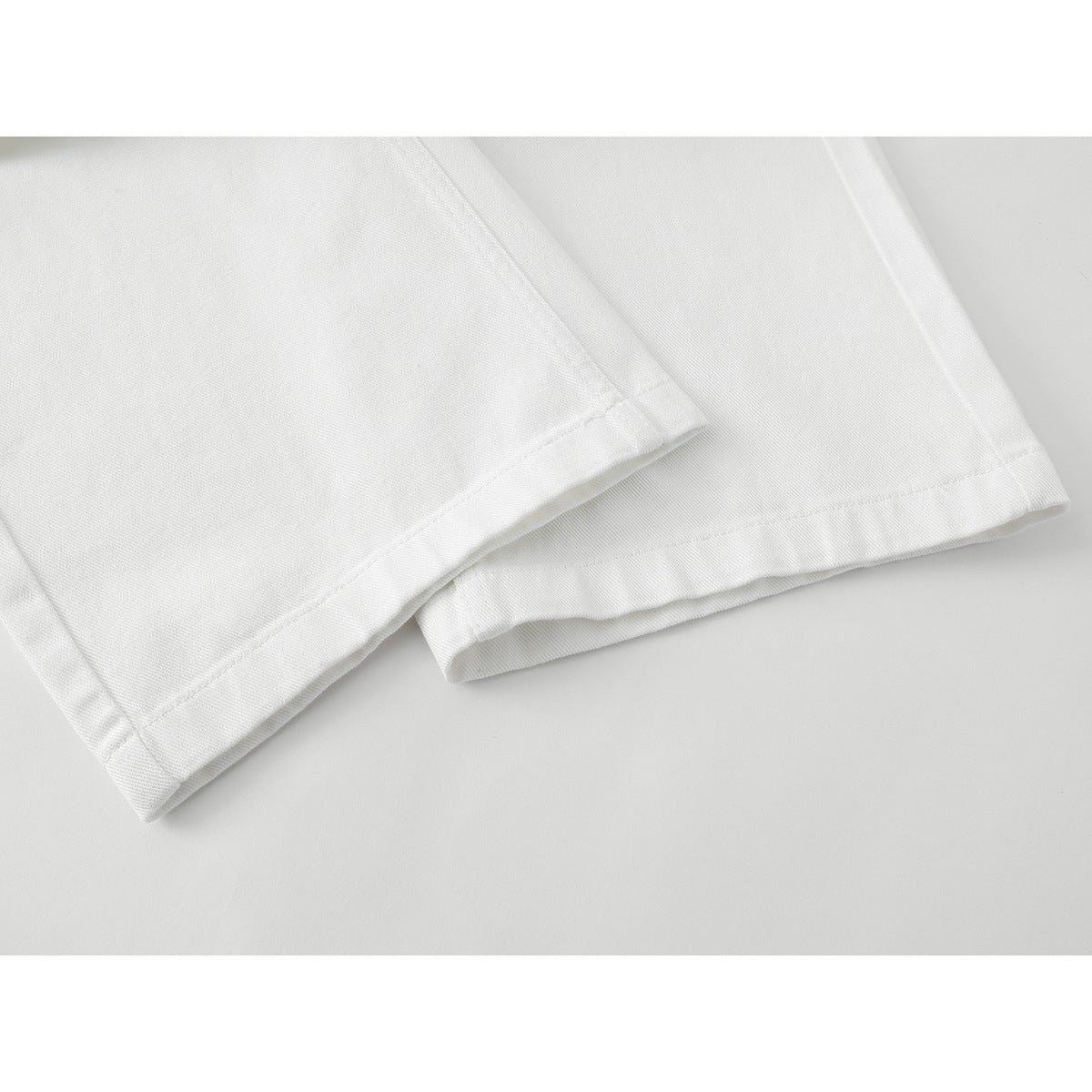 Close-up of the hems and lower legs of white wide-leg pants.