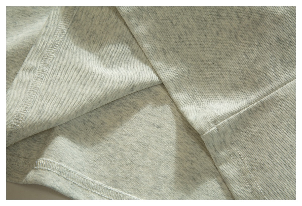 Close-up of pale heather gray fabric showing overlocked seams and stitched edges.