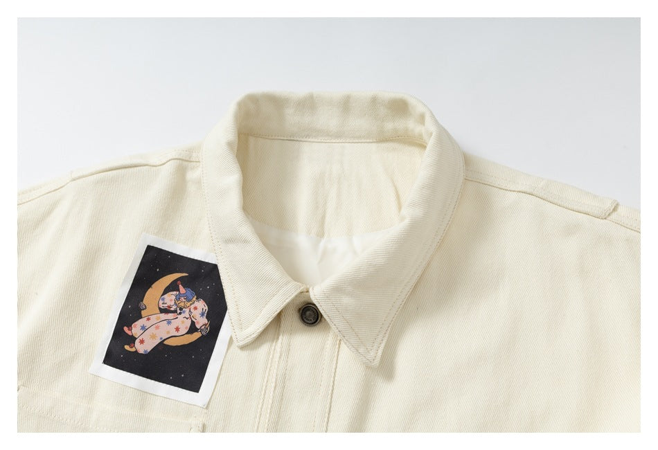 Close-up of the ivory jacket collar, dark button and illustrated patch on the upper chest.