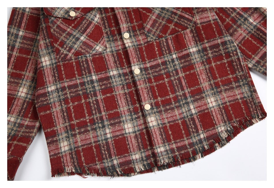 Close view of a red, cream, and charcoal plaid shirt front with pale buttons and a frayed hem.