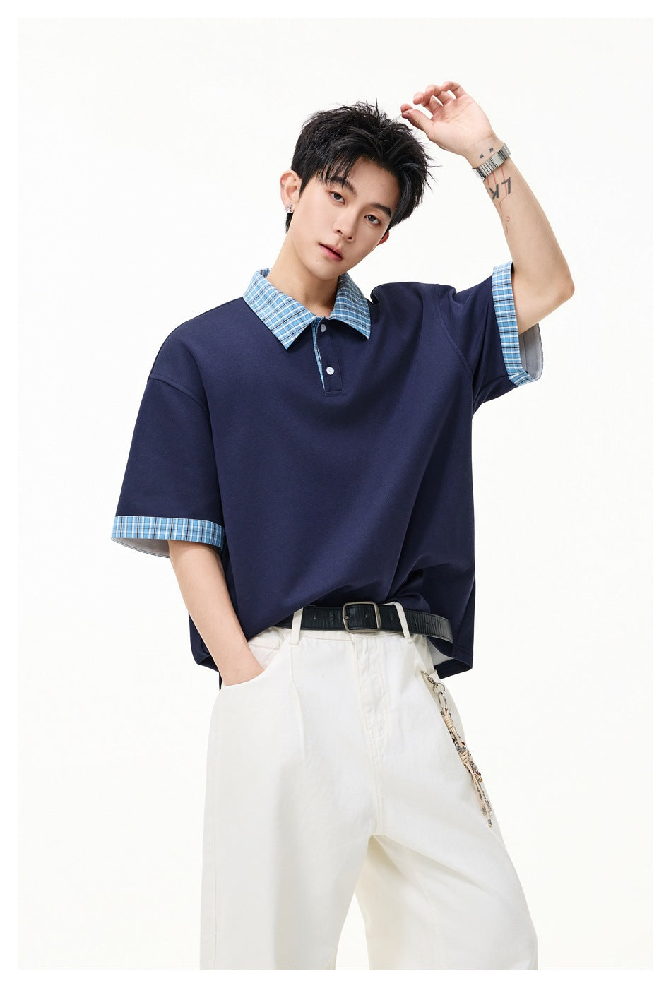 Model wearing a navy short-sleeve polo with a blue plaid collar and cuffs and a short button placket.
