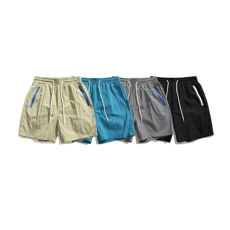 Four pairs of drawstring shorts displayed together in pale khaki, turquoise, gray, and black.