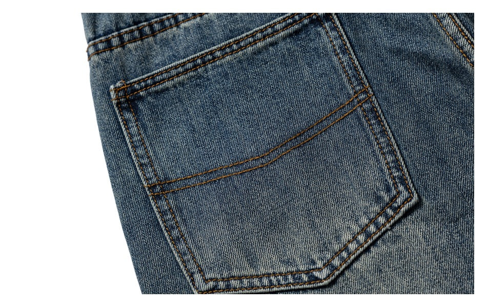 Close-up of a back patch pocket on medium-wash jeans with brown contrast stitching.
