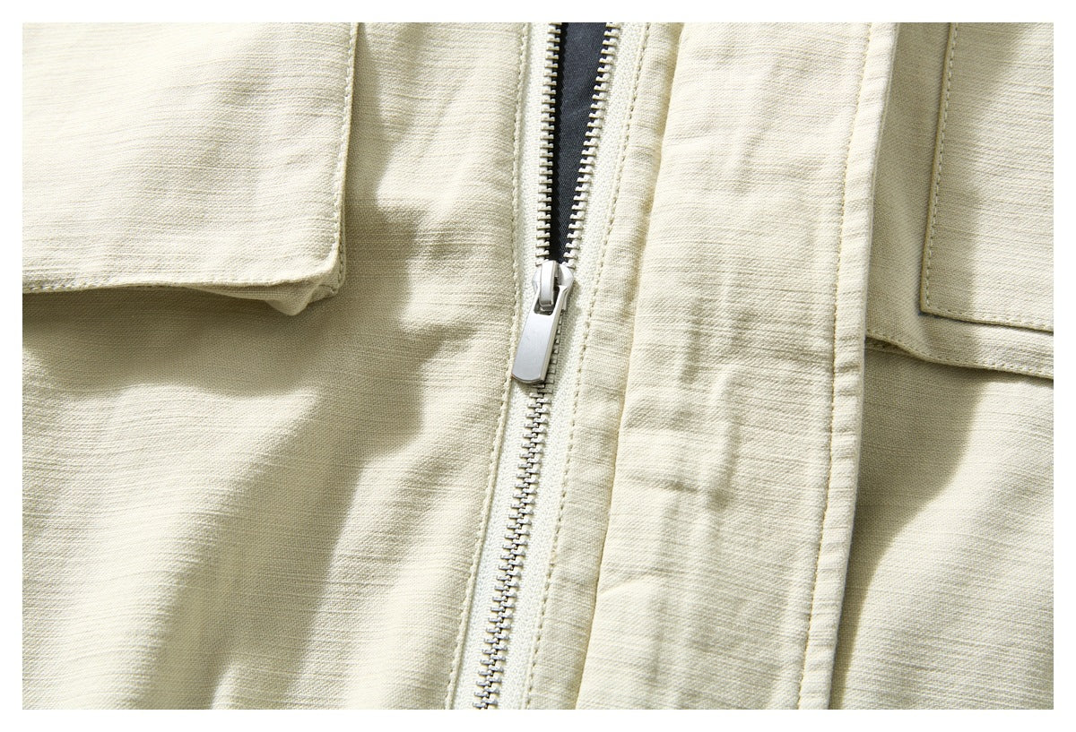 Close-up of the ivory jacket's front silver zipper, placket and flap pocket edges.