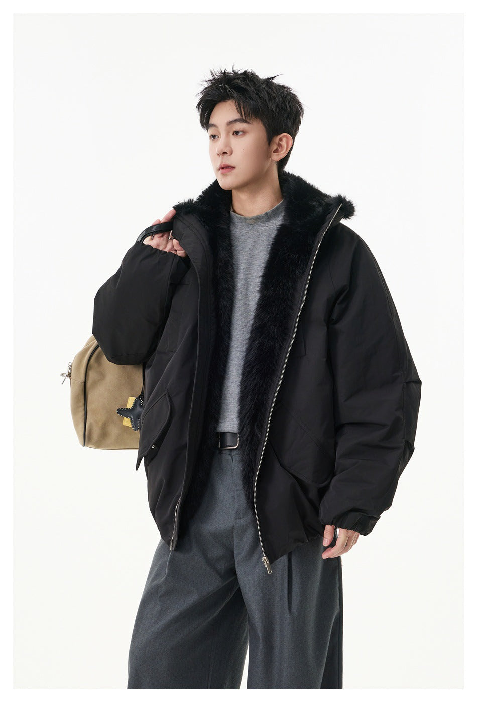 A model wears an open black oversized jacket with plush black trim, shown with a shoulder bag.