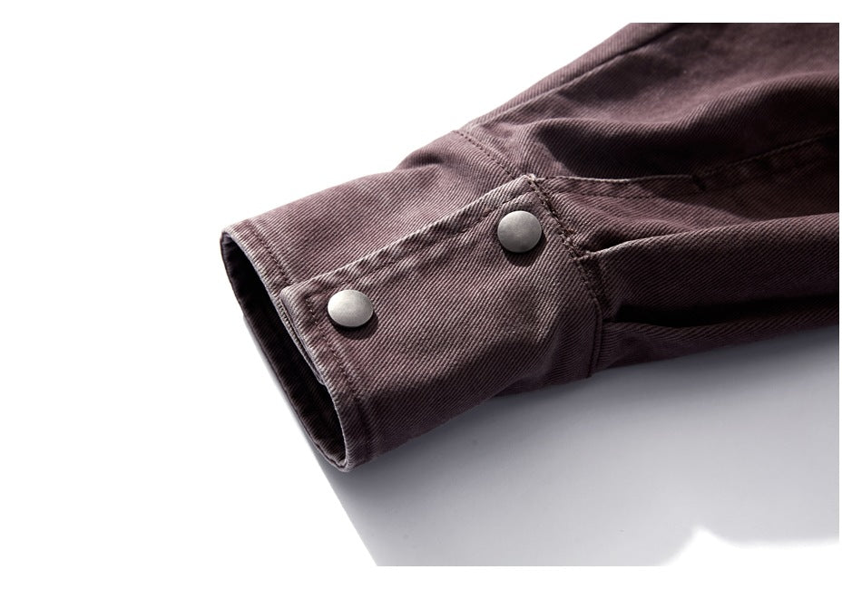 Close-up of a muted plum-brown jacket cuff with two round metal snap buttons.