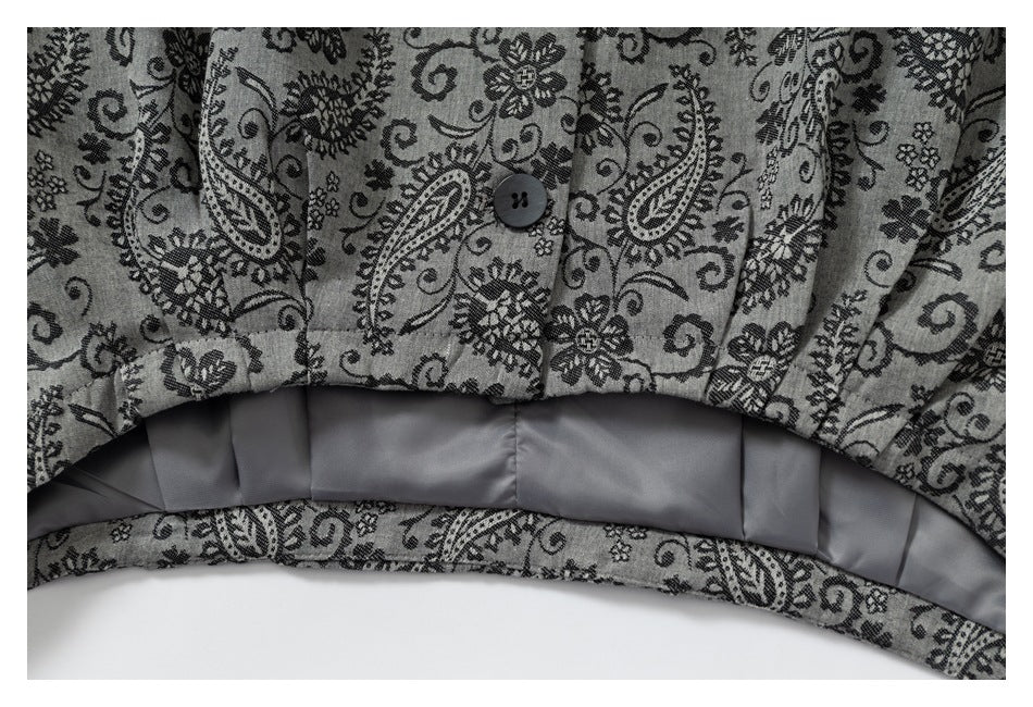 Close-up of the jacket's patterned lower edge, button, and gray pleated interior lining.