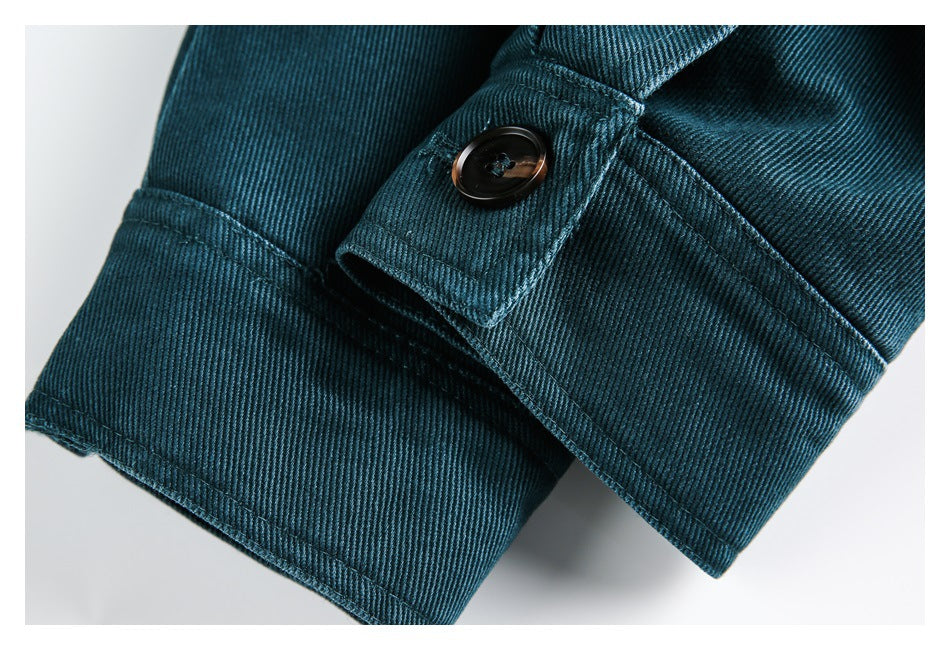 Close-up of a buttoned cuff tab on a teal twill sleeve.