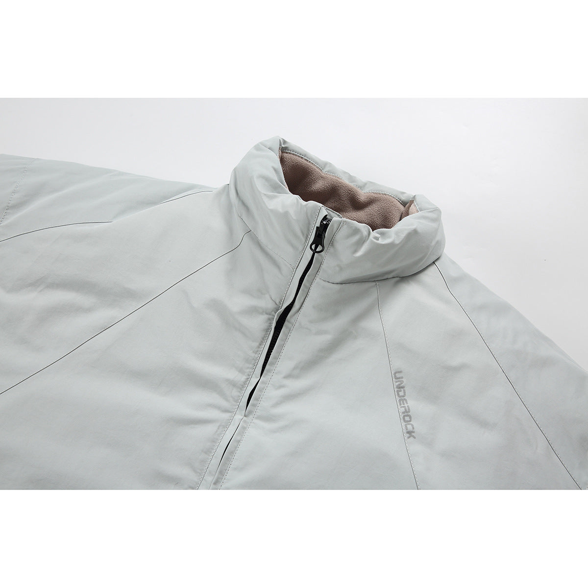Close-up of a pale gray jacket collar, black front zipper, taupe lining, and subtle chest logo.