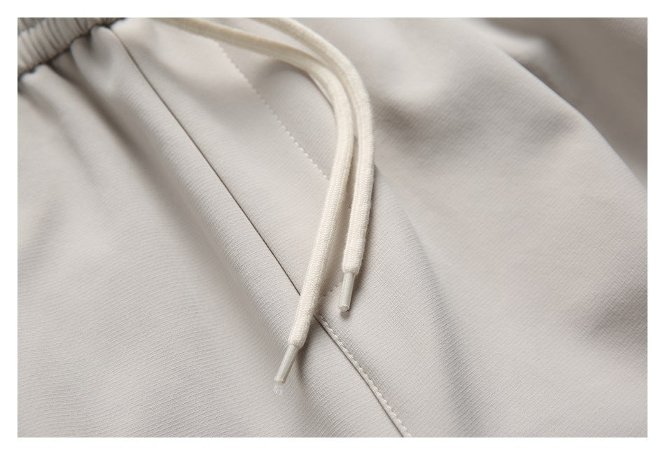 Close-up of cream drawstrings and stitched seam on light beige joggers.