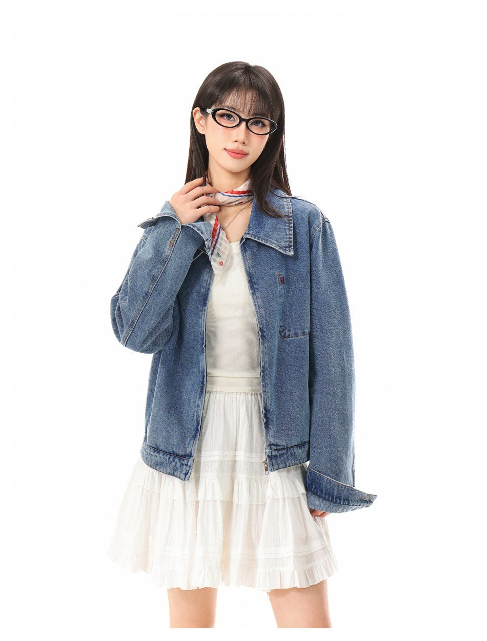 Closer front view of a model wearing an open blue denim jacket over a white top and tiered ruffle skirt.