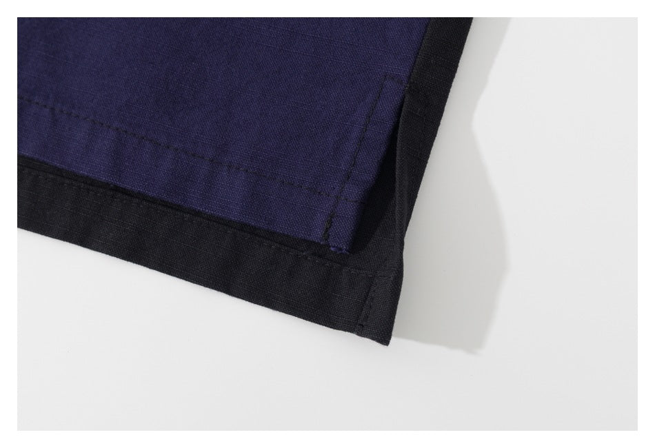 Close-up of a dark indigo garment hem with black trim and visible stitching.