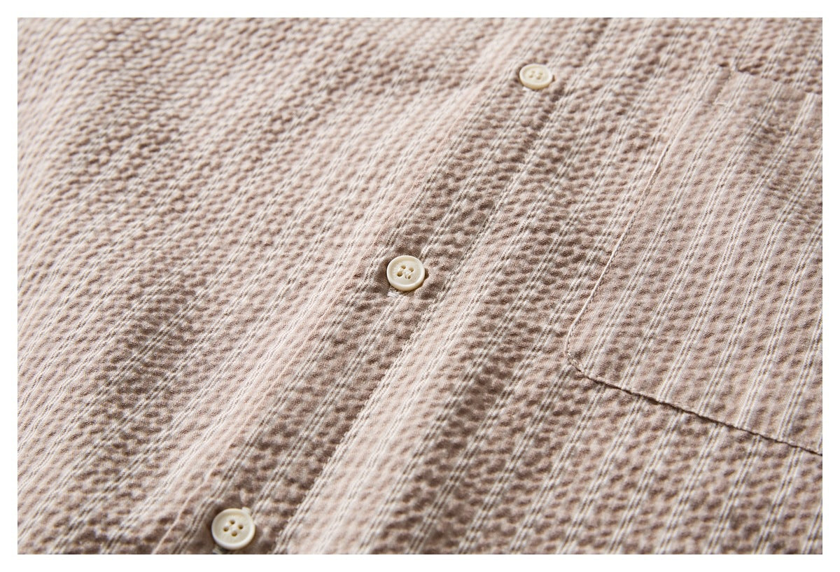 Close-up of the button placket and chest pocket on a beige-brown patterned shirt.