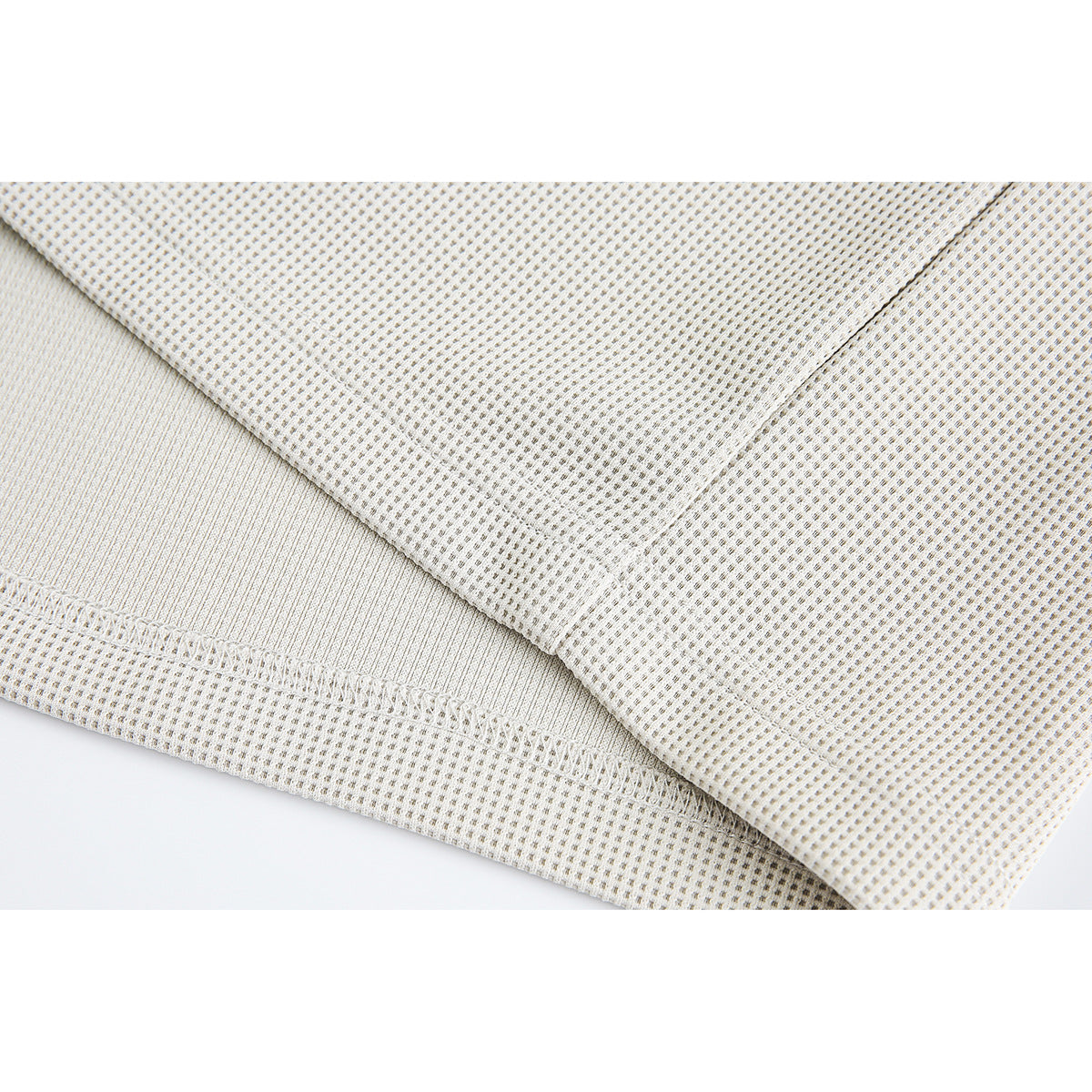 Close-up of cream-colored textured fabric, folded to show the seam and ribbed edge.