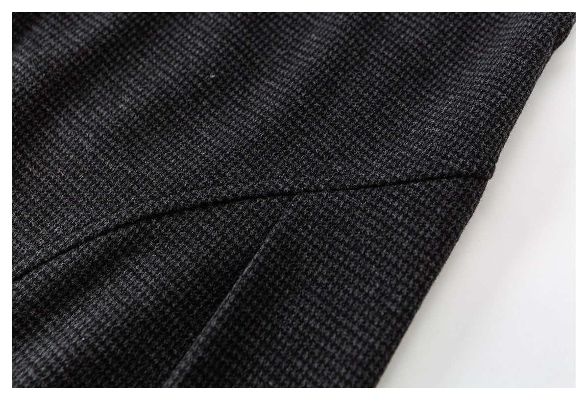 Close-up of dark charcoal and gray patterned trousers showing a curved seam and fabric texture.