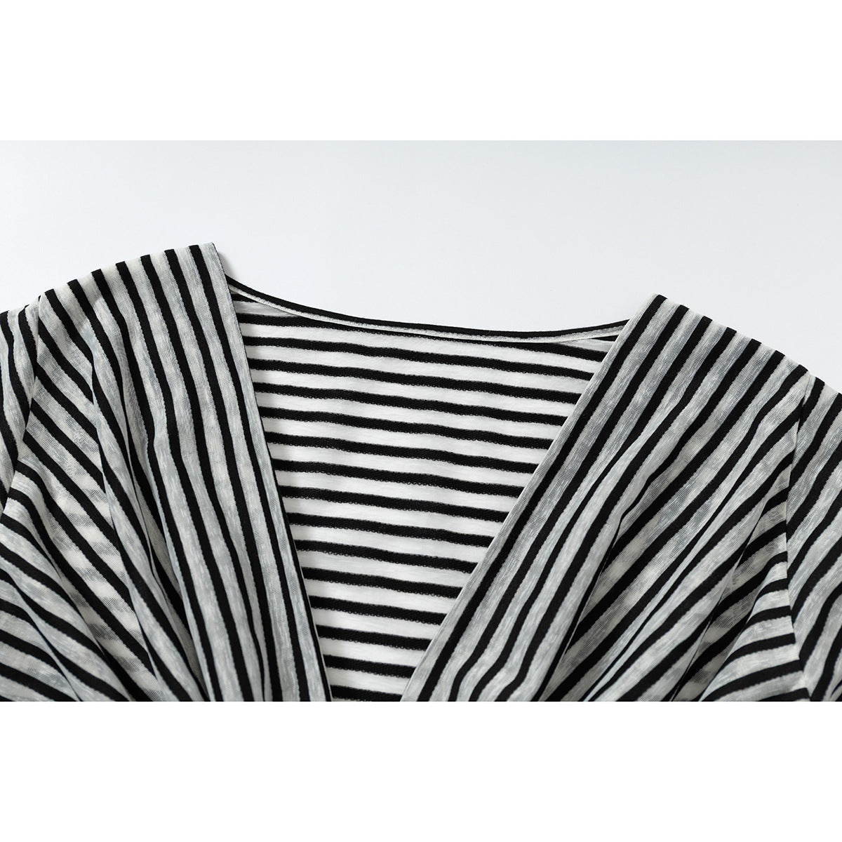 Close-up of a black and gray striped top with a draped neckline over a horizontally striped inner layer.