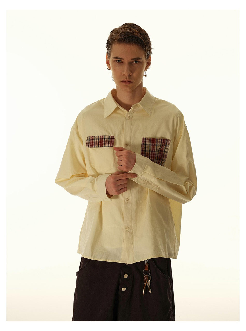 Front view of a model wearing a pale cream shirt with plaid chest pockets and button cuffs.