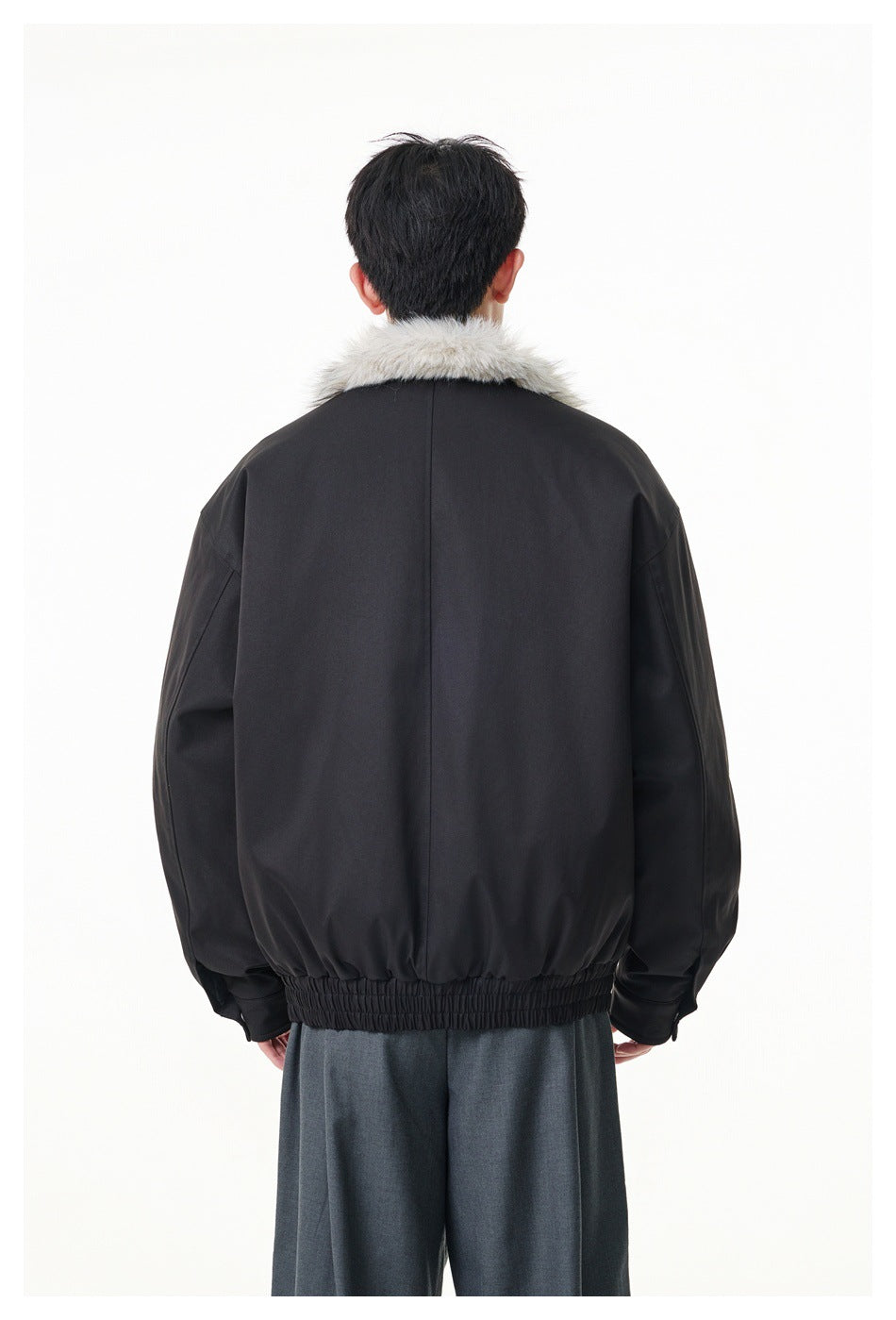 Back view of a model wearing a black jacket with a light gray fur collar and gathered hem.