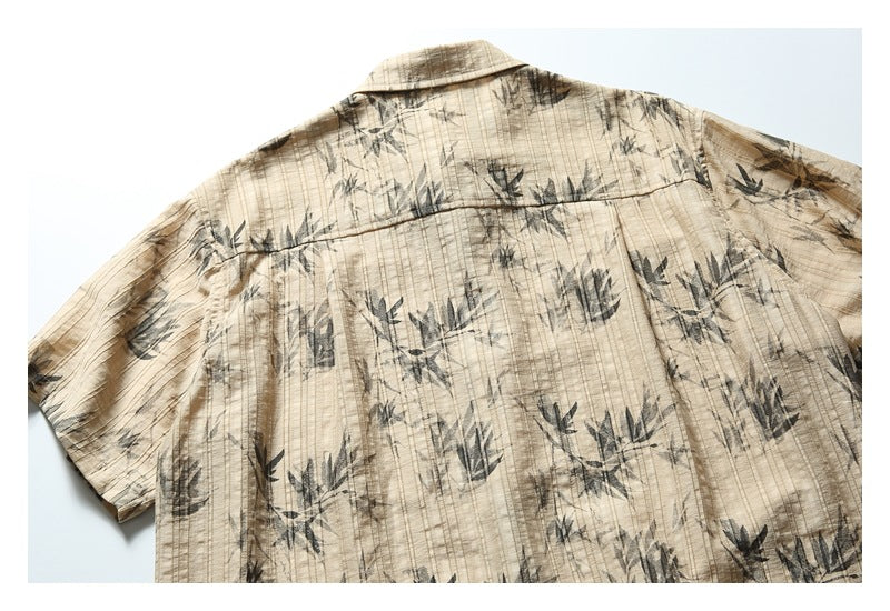 Back view of a beige short-sleeve shirt with dark botanical print and a back yoke seam.
