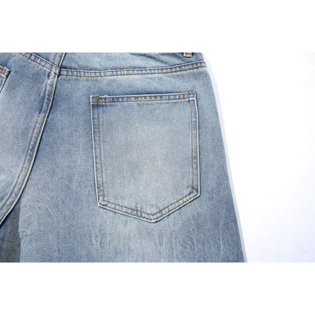 Close-up of a back pocket and stitching on light blue washed denim shorts.