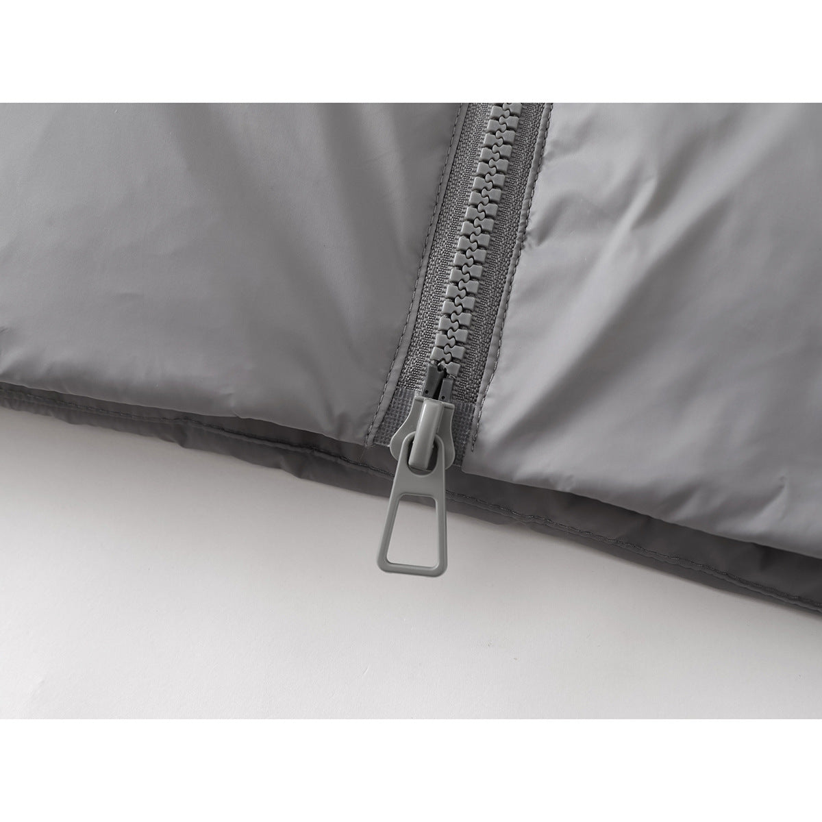 Close-up of the gray jacket's large front zipper pull and lower hem.