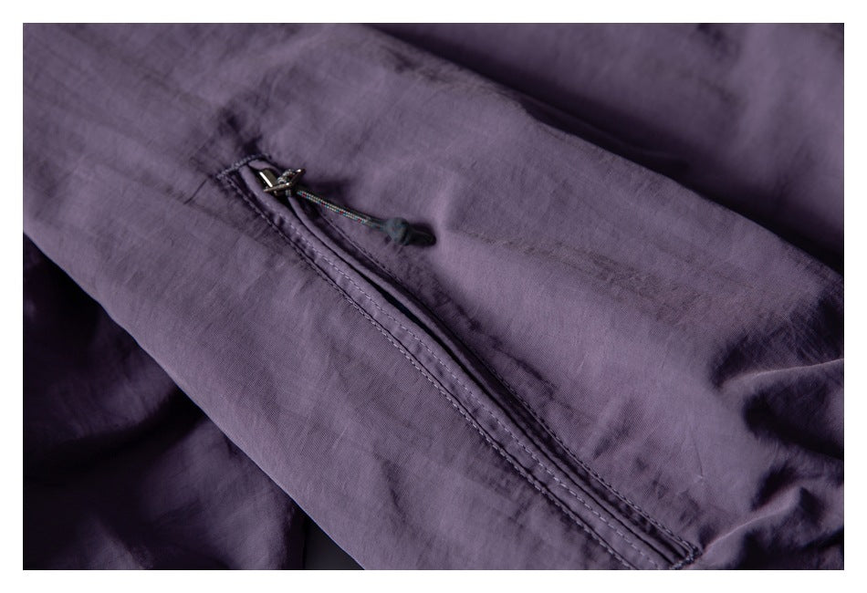 Close-up of a slanted zip pocket with a cord pull on purple fabric.